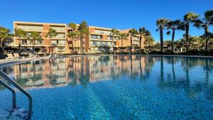 a large swimming pool with palm trees and buildings at Herdade dos Salgados,T3 8C-0C, Vila das Lagoas in Albufeira