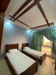 two beds in a room with a window at ELFA APPARTEMENTS Familiaux in Agadir