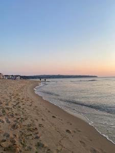 uma praia ao pôr do sol com pessoas caminhando na água em Prostor Apartments em Obzor