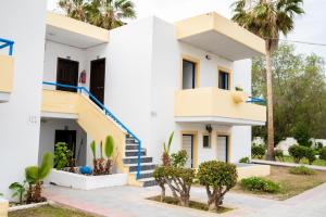 a white house with blue stairs and palm trees at Kos Olympia Apartment superior in Kos Town