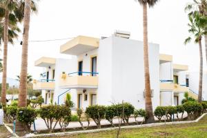 a white building with palm trees in front of it at Kos Olympia Apartment superior at Lambi Beach in Kos Town