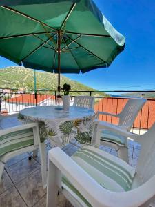 a table and chairs with a green umbrella on a patio at Apartmani Ines in Marina
