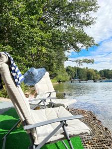 2 chaises assises sur la rive d'un lac dans l'établissement Pokoje nad jeziorem z opcją szkolenia żeglarskiego, à Pluski