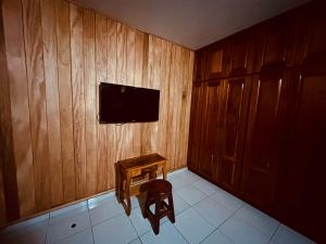 Habitación con pared de madera, mesa y TV. en Residencial Coya en David