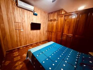 1 dormitorio con 1 cama azul y paredes de madera en Residencial Coya en David