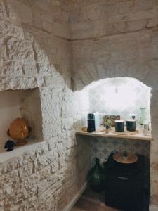 eine Küche mit einer Steinmauer mit einer Theke und einem Regal in der Unterkunft Casa De Amicis in Sammichele di Bari