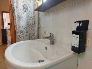 un lavandino bianco in bagno con dispenser di sapone di casa delle margherite Ladispoli a Ladispoli