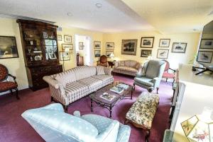 una mujer sentada en una sala de estar con sofás y sillas en Blairpen House Country Inn, en Niagara on the Lake