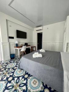 Dormitorio con cama, escritorio y TV en TEA Luxury - Praia a Mare, en Praia a Mare