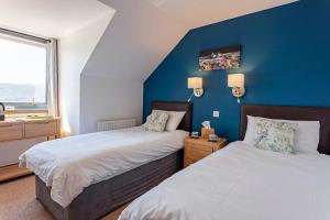 a bedroom with two beds and a blue wall at Lochbroom Lodge in Ullapool