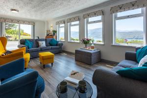 uma sala de estar com sofás, cadeiras e janelas em Lochbroom Lodge em Ullapool