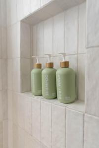 three green bottles sitting on a shelf in a bathroom at The Laurel Loft in San Diego