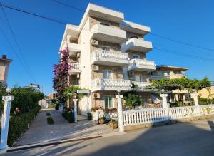 a large white building with balconies and flowers on it at Apartments Cota Guesthouse in Ulcinj