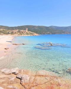 a beach with blue water and rocks and trees at Casa vacanza Il Podere in Teulada
