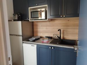 cocina con armarios azules y microondas en Confort sur le port, en Gruissan