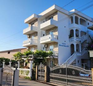 a white building with a fence in front of it at Apartments Cota Guesthouse in Ulcinj