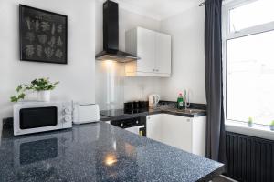 eine Küche mit einer Arbeitsplatte mit Mikrowelle in der Unterkunft Central 2 Bedroom House-Parking in Bishop Auckland + 22 Fotos
