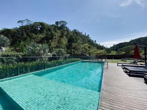 a large swimming pool with a wooden deck next to a mountain at The Green Hill com piscinas em Praia Brava in Itajaí