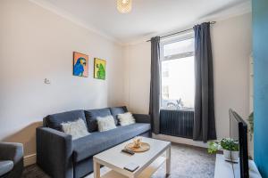 a living room with a blue couch and a window at Central 2 Bedroom House-Parking in Bishop Auckland