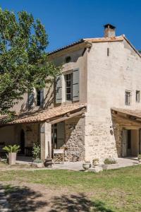 une grande maison en pierre avec un arbre en face de celle-ci dans l'établissement Campagne Volver, à Arles