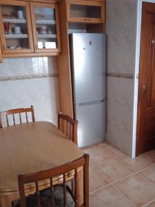 eine Küche mit einem Tisch und einem weißen Kühlschrank in der Unterkunft Casa Puerta del Sol in Moaña