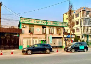 two cars parked on a street in front of a building at Guest house by Sayohati Diyor in Dushanbe