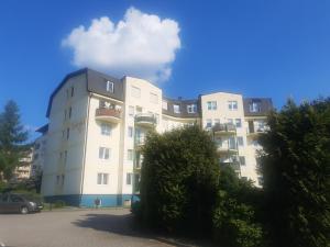 a tall white building with a cloud in the sky at Na Złotych Łanach - apartament z parkingiem in Bielsko-Biała