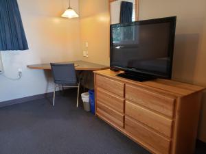 a room with a television on a dresser with a desk at Lamplighter Inn in Three Hills