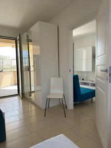 Cette chambre comprend une chaise blanche et un canapé bleu. dans l'établissement Casa Vacanze Matilde Marzamemi, à Marzamemi