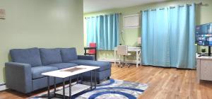 Modern 2BR Apartment Jamaica Queens NYC في Hillside: غرفة معيشة مع أريكة زرقاء وطاولة