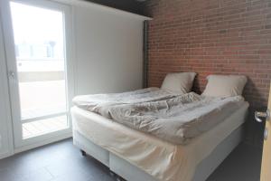 a bed in a room with a brick wall at Vesterhavsgade 47. door 25 (id. 076) in Esbjerg