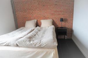 a bed with white sheets and a brick wall at Vesterhavsgade 47. door 25 (id. 076) in Esbjerg