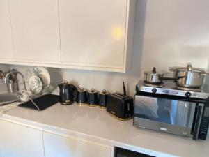 a kitchen counter with a stove and a microwave at Studio Apartment in Dartford, 5mins to Stn & High Str. in Kent