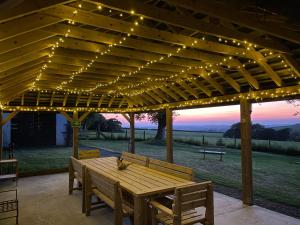 a wooden table under a pergola with lights at Primrose in Holsworthy