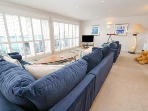 a large blue couch in a living room with windows at Sandbanks in Penzance