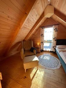 um quarto no sótão com uma cadeira, uma cama e uma janela em La Jolla Domki Drewniane em Jarosławiec