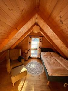 um quarto no sótão com uma cama e uma cadeira em La Jolla Domki Drewniane em Jarosławiec