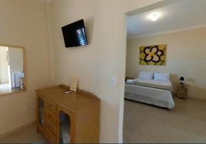 a bedroom with a bed and a television on the wall at Pousada do Lago Dutra in Guapé