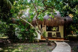 une petite maison avec deux chaises et un toit de paille dans l'établissement Hotel Rancho Encantado, à Bacalar