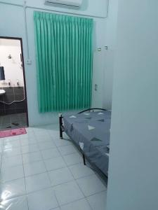 une chambre d'hôpital avec un lit et un rideau vert dans l'établissement Homestay Kak Pah Kota Bahru, à Kota Bharu