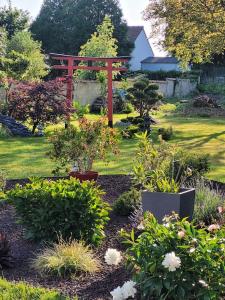 einen Garten mit einem roten Tor und einigen Pflanzen in der Unterkunft Gite le Ryokan in Wailly-Beaucamp