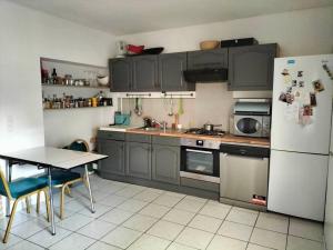 uma cozinha com armários cinzentos, uma mesa e um frigorífico em House close to the city center em Mons