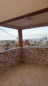 d'une terrasse avec un mur en briques et un plafond. dans l'établissement Appart avec terrasse El Ouatia Tan Tan Plage, à Tan-Tan Plage