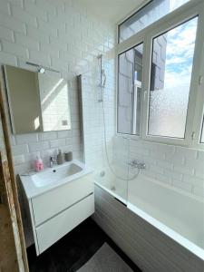 baño blanco con lavabo, bañera y ventana en The Oasis apartment, 2 bedrooms antwerp South, en Amberes