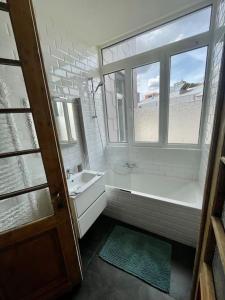 baño con bañera, lavabo y ventana en The Oasis apartment, 2 bedrooms antwerp South, en Amberes