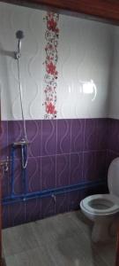 a bathroom with a toilet and purple and white tiles at Appart avec terrasse El Ouatia Tan Tan Plage in Tan-Tan Plage