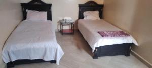 dwa łóżka siedzące obok siebie w pokoju w obiekcie Appart avec terrasse El Ouatia Tan Tan Plage w mieście Tan-Tan Plage