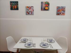 a white table with chairs and plates on it at Casa Aprosio, appartamento luminoso in centro a Ventimiglia, a 5 min dal mare e dal treno in Ventimiglia