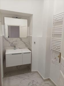 a white bathroom with a sink and a mirror at Casa Aprosio, appartamento luminoso in centro a Ventimiglia, a 5 min dal mare e dal treno in Ventimiglia