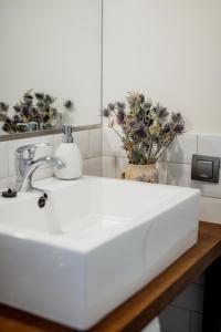 un lavabo blanco con un jarrón de flores en Luxury apartment close to the sea, en Kuressaare